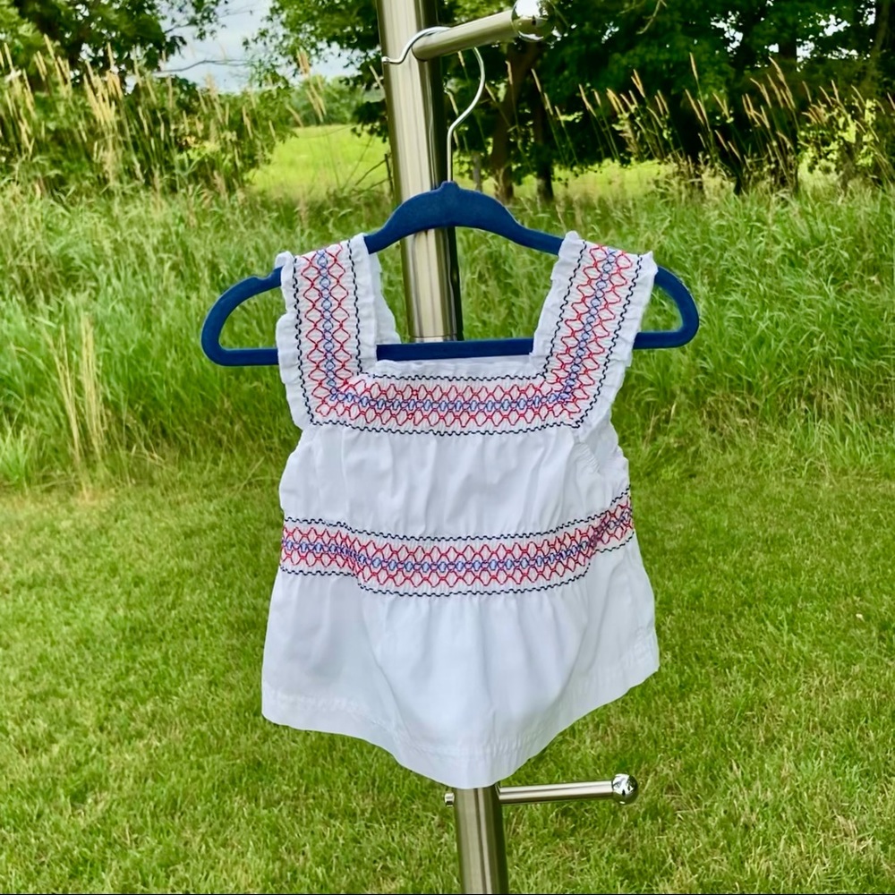 OshKosh: Girls white sleeveless top w/ red, white & blue smocking.  Size 3-6 mos